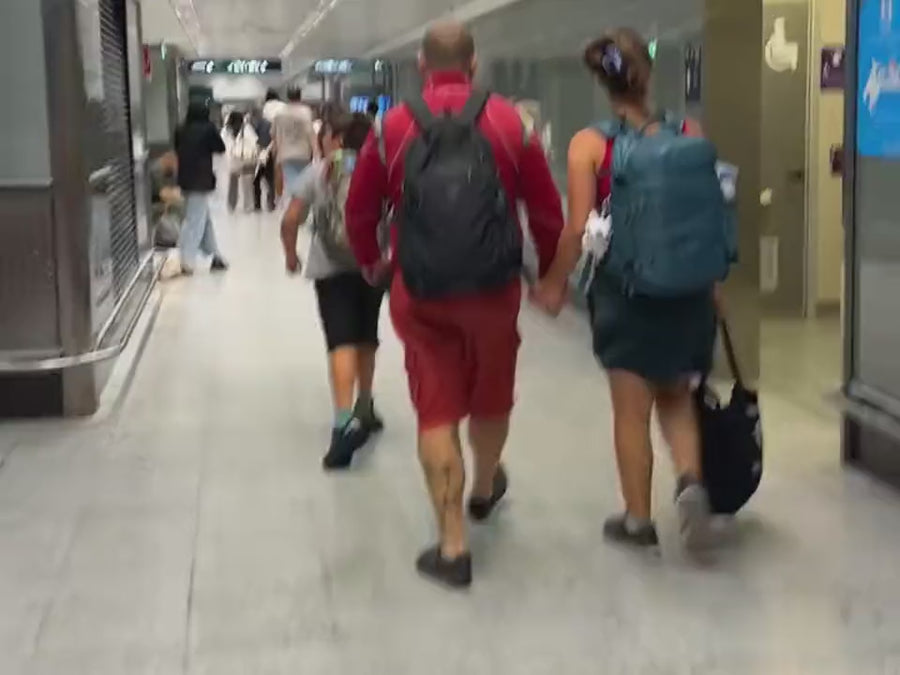 A family walking through the airport, each with their own backpack